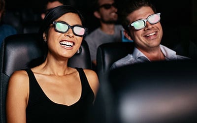 Two people wearing 3D glasses watching a movie in a movie theatre