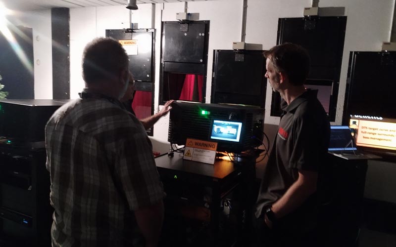 Two people watching a cinema projector demonstration