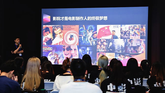 Students sitting in a large conference centre listening to a presentation about cinema in China.
